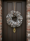 Frosted pinecone Christmas wreath hanging on a front door.